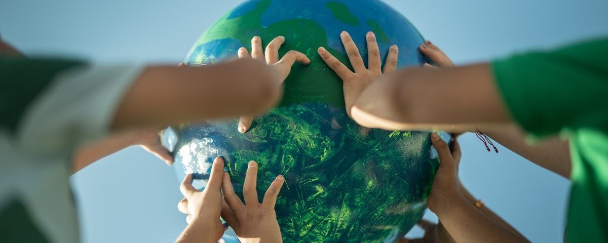 Des enfants tenant une planète à l’extérieur.