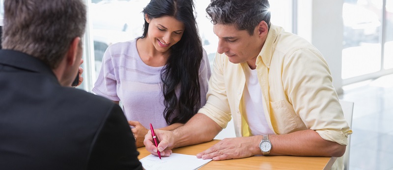 Un professionnel de l'assurance faisant signer un contrat d'assurance à un couple
