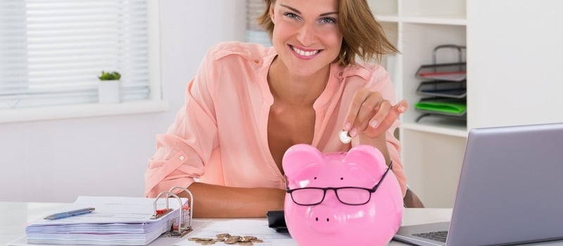 Une femme insérant une pièce de monnaie dans une tirelire en cochon