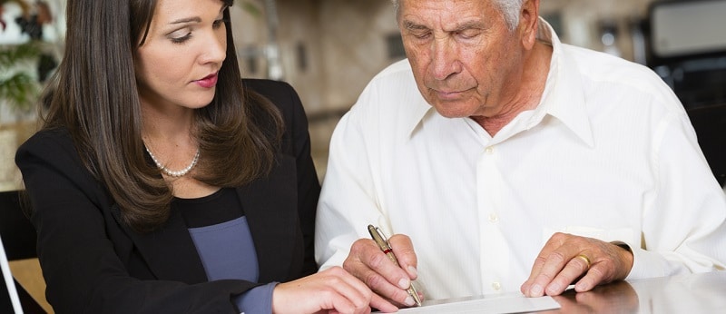 Une personne âgée en train de signer un contrat d'assurance