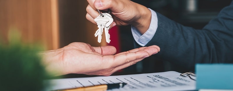 Agent immobilier donnant des clés de la maison à la femme et signe d'un accord au bureau