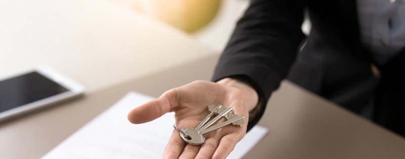 Concept de transaction immobilière. Homme tenant en main les clés, offrant des biens à vendre et à louer. 