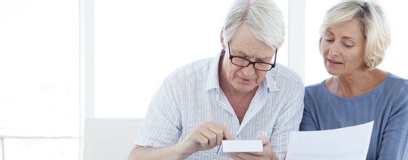 Couples senior faire compter leurs finances à la maison devant l’ordinateur portable.