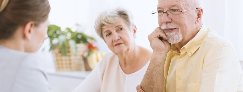 Couple de personnes âgées lors de la réunion avec l'agent d'assurance à l'écoute d'une offre.
