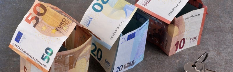 Maisons en billets de banque en euro avec un trousseau de clés sur fond gris.