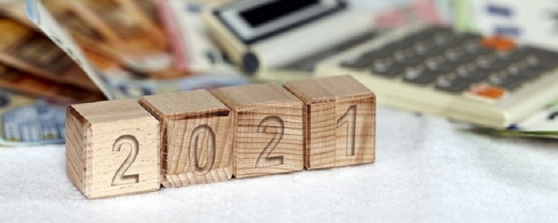 Boites en bois avec l’écriture 2021 dont des billets et argents et un calculatrice comme fond.