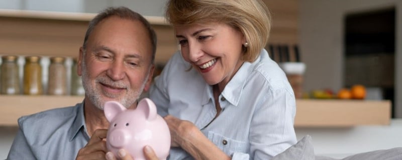 Portrait d'un couple de personnes âgées à la maison et tenant leurs économies dans une tirelire â home finances concepts.