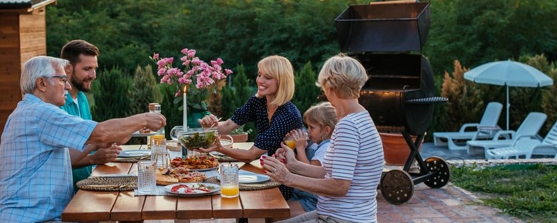 Famille heureuse et joyeuse prenant un repas ensemble dans le jardin.