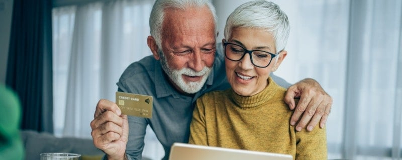 Couple d'âge mûr faisant des achats en ligne avec une carte de crédit et une tablette numérique.