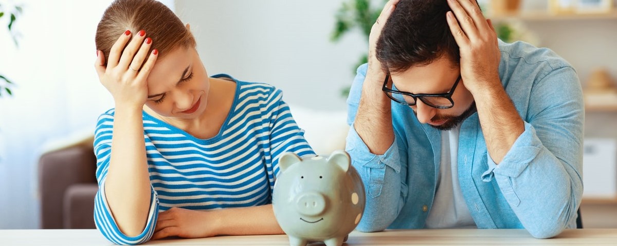 Planification financière famille en faillite couple stressé avec tirelire à la maison.