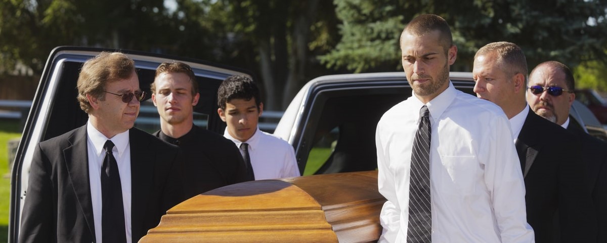 Un groupe d'hommes portant un cercueil lors d'un enterrement.