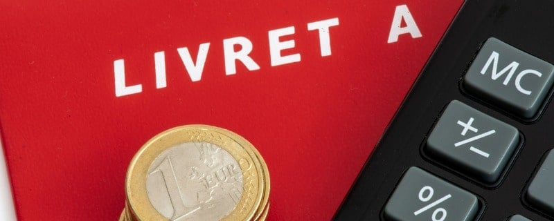 France : Livret A avec une pile de pièces d'euros et une calculatrice.