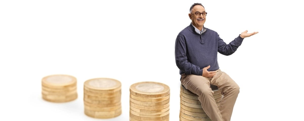 Homme mûr assis sur la plus haute pile de pièces de monnaie et montrant avec la main isolée sur fond blanc.