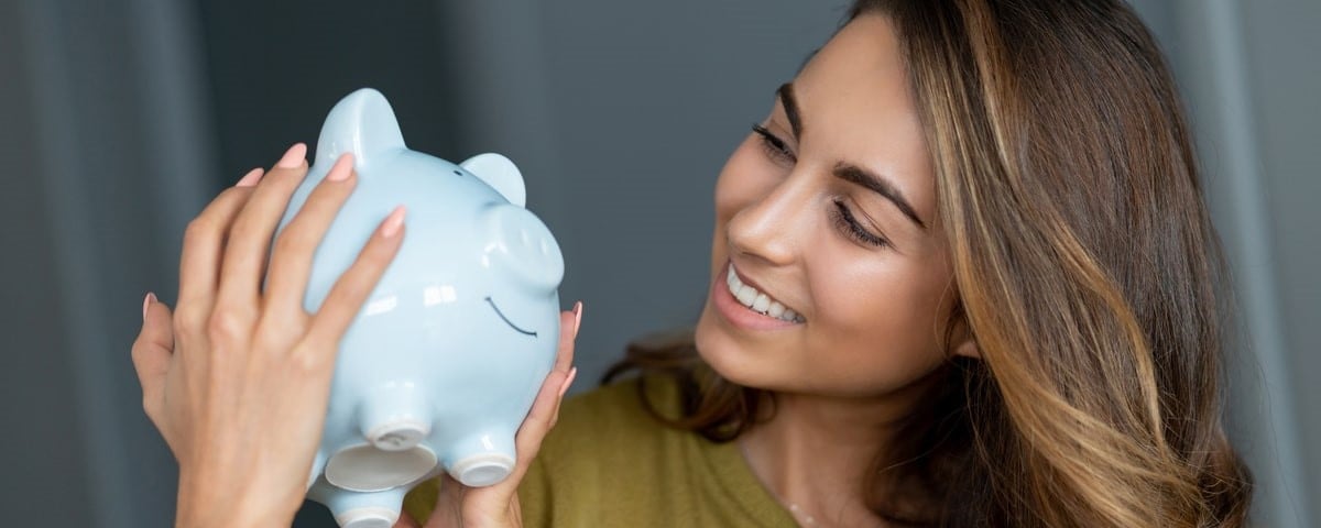 Portrait d'une femme heureuse économisant de l'argent dans une tirelire - concepts de finances personnelles.