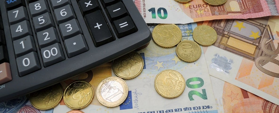 Monnaie en euros, billets de banque et pièces de monnaie avec calculatrice sur une table.