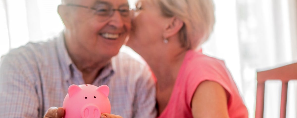 Epargne retraite pour un couple de seniors, Couple de seniors heureux avec une tirelire