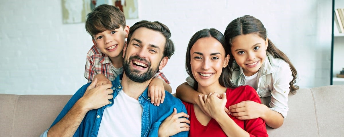 Une jeune famille heureuse se détend à la maison en se souriant et en se serrant dans les bras.