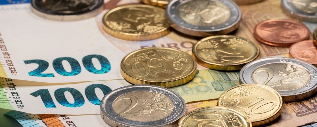 Gros plan sur des billets de banque en euros surmontés de pièces de monnaie.