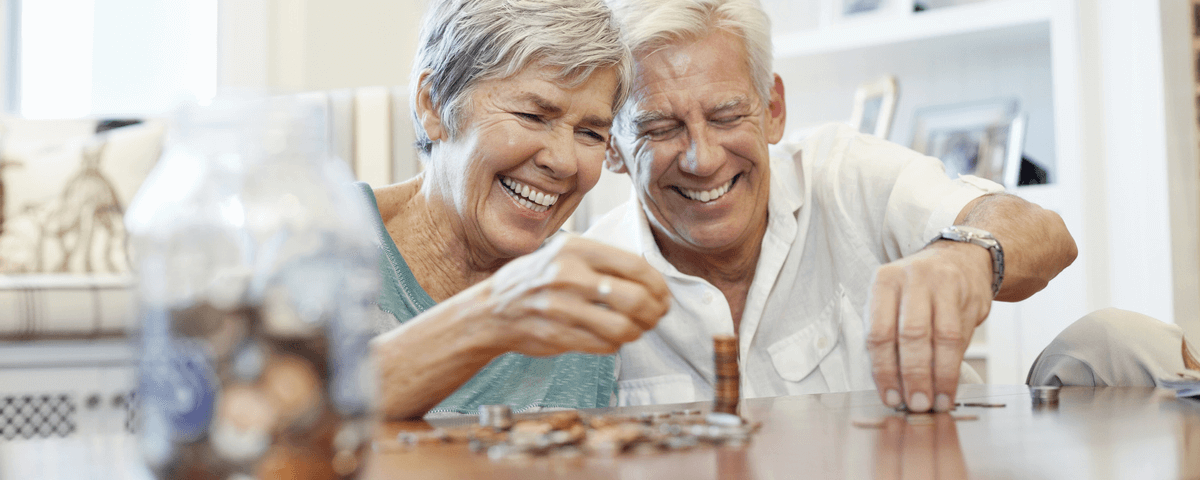 Couple de seniors enjoués comptant les pièces de monnaie à une table.