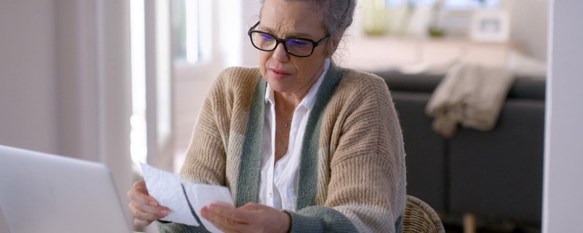 Femme agée lisant des notes devant un ordinateur