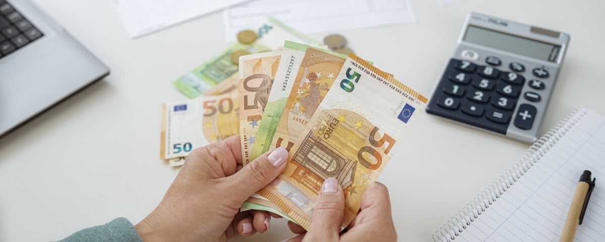 Gros plan sur les mains d'une femme qui compte les billets de banque en euros et planifie les finances de la maison.