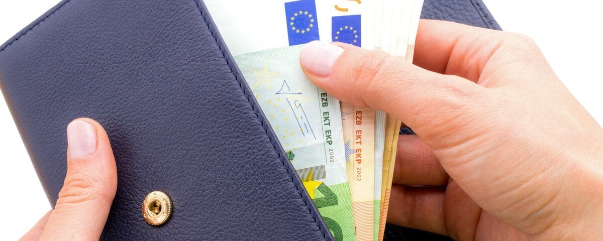 Porte-monnaie bleu avec des euros dans les mains isolé sur fond blanc