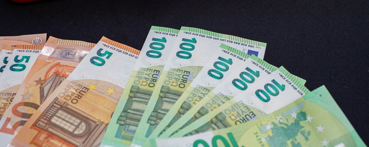 un grand nombre de billets de banque en euros sont étalés devant une caisse rouge
