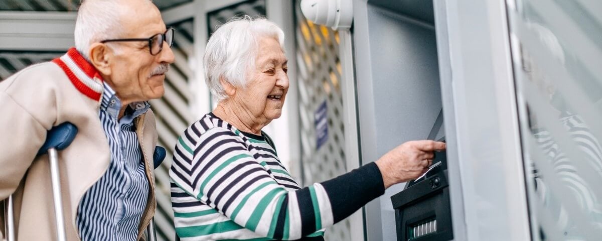 Couple de personnes âgées utilisant un distributeur automatique de billets dans la rue