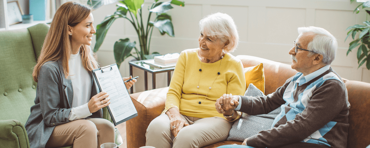 Couple de seniors s'entretenant avec une conseillère financière ou immobilière à domicile.