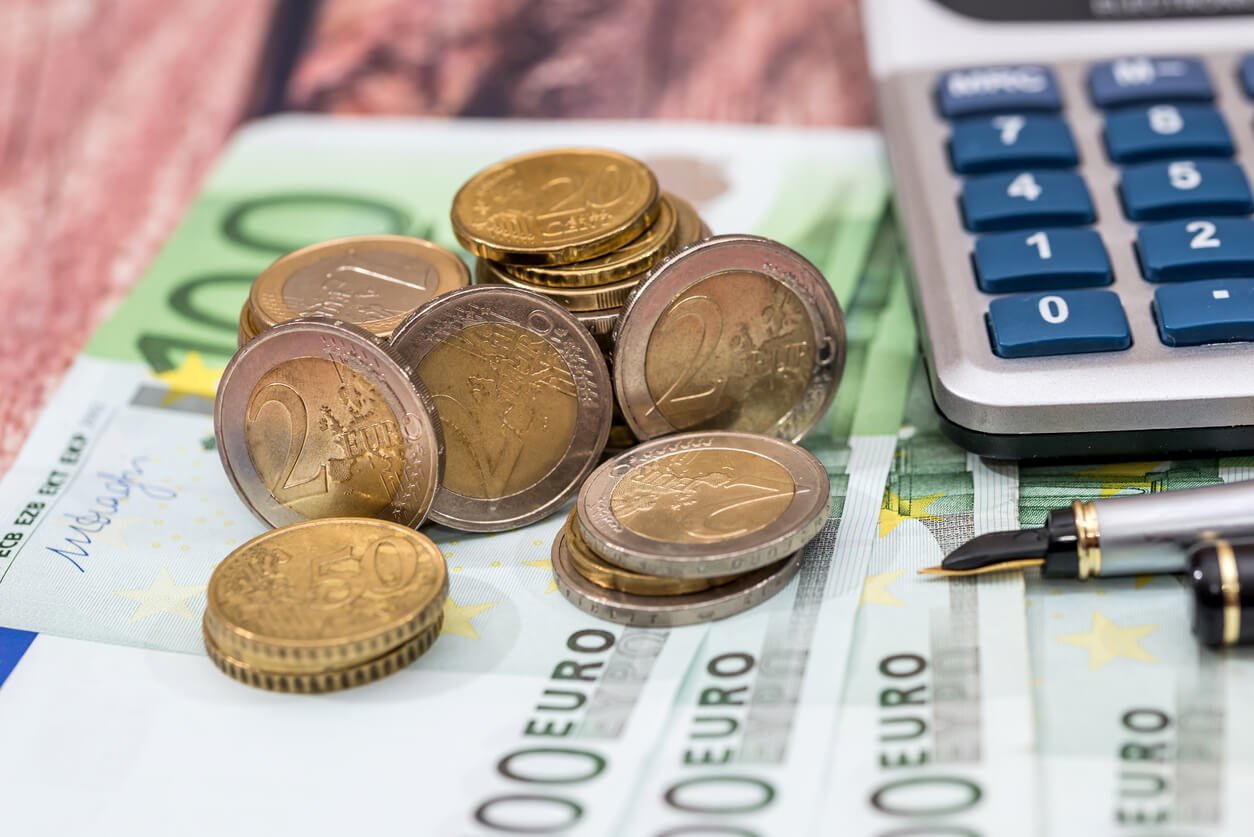Billets de 100 euros avec stylo à encre, pièce de monnaie et calculatrice.