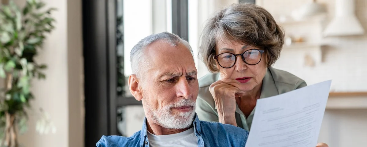 Grands-parents âgés lisant des documents, ayant des problèmes de dette avec perte d’argent