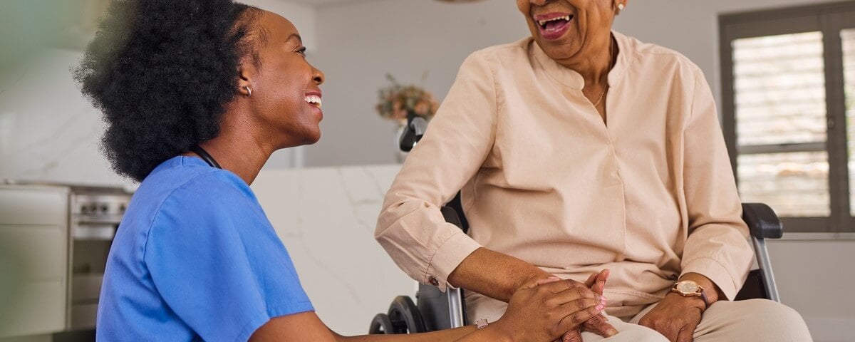 Heureuse soignante africaine aidant une personne âgée handicapée ou un patient à domicile.