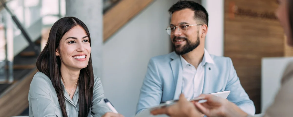 Un agent d’assurance confiant remplit des documents dans un bureau avec des clients. 