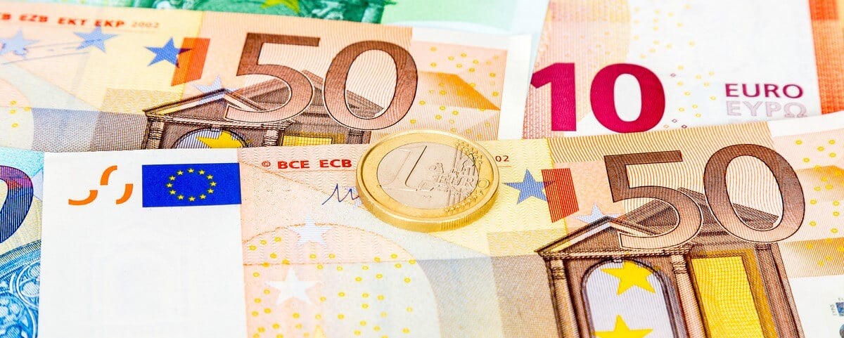 Pièce de monnaie en euros posée sur des billets de banque en euros, gros plan