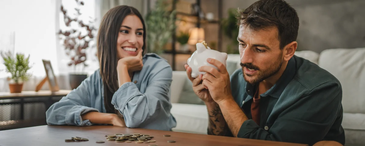 Un couple d'adultes met de l'argent de côté dans la tirelire à la maison.