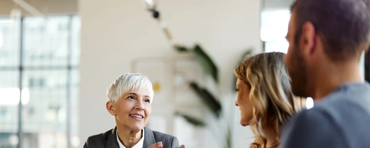 Agent financier senior heureux communiquant avec un couple lors d'une réunion au bureau.