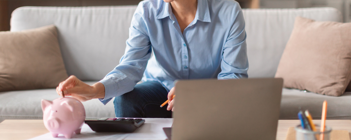 Heureuse femme mûre européenne tenant mettre de l’argent dans la tirelire à l’intérieur.