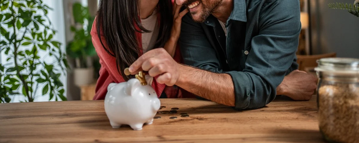 Jeune couple heureux économisant de l'argent dans une tirelire.