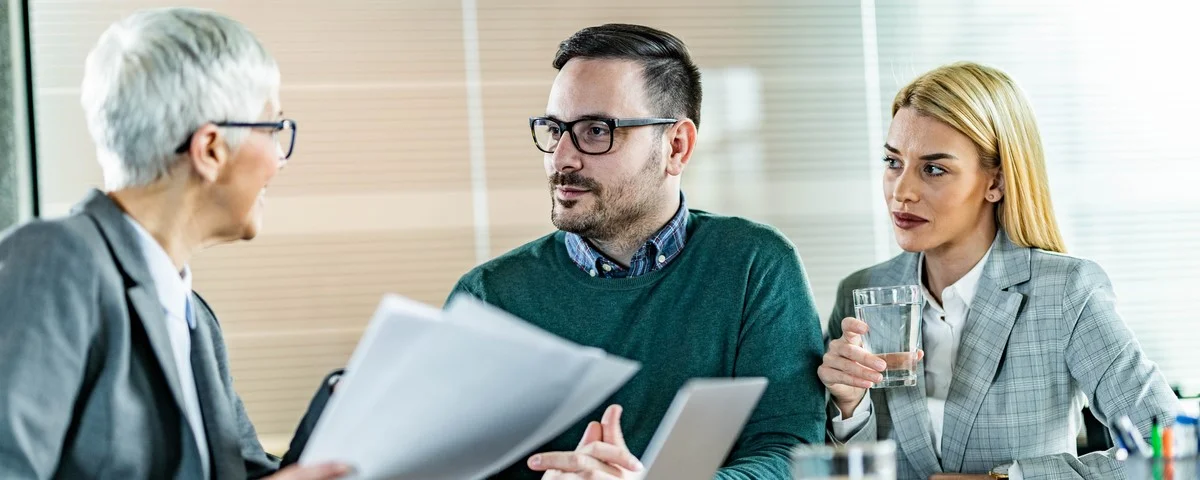 Jeune couple communiquant avec son agent financier lors d'une réunion au bureau.