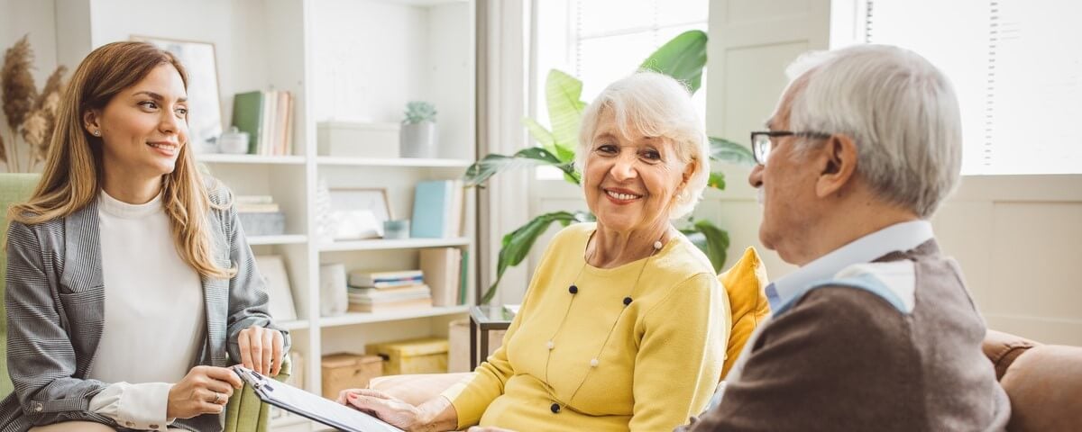 Couple âgés s'entretenant avec une conseillère financière ou immobilière à domicile.