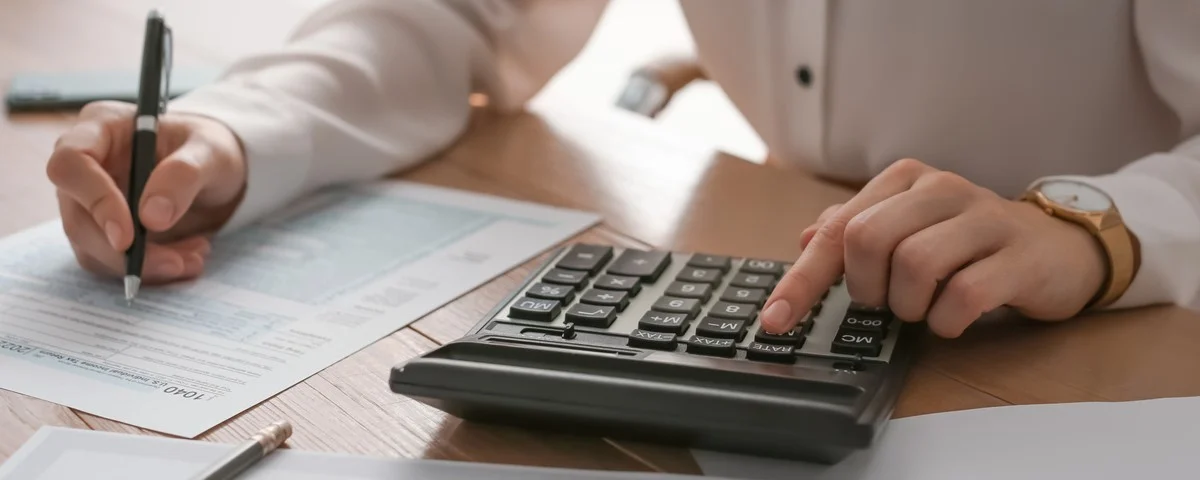 Comptable fiscal travaillant à une table dans un bureau avec une calculatrice, gros plan.