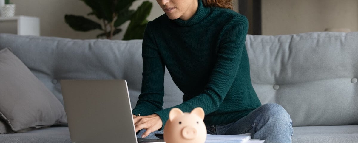 Jeune femme intelligente et concentrée gérant les dépenses domestiques dans une application informatique de banque en ligne, planifiant des investissements futurs ou épargnant de l'argent.