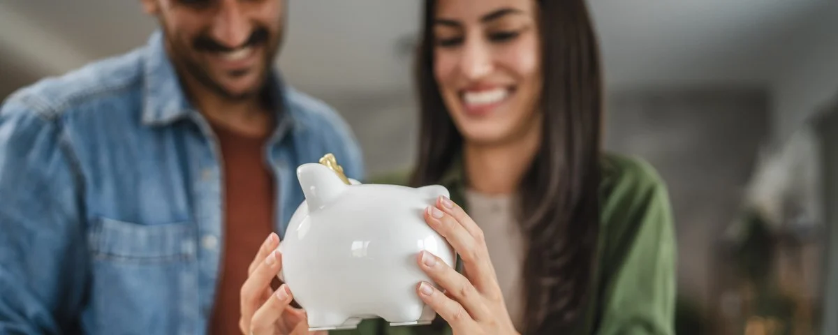 Un couple d'adultes met de l'argent de côté dans la tirelire à la maison.