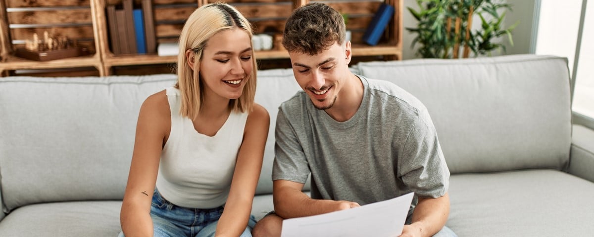 Jeune couple caucasien souriant, heureux de contrôler l'économie familiale en utilisant un ordinateur portable à la maison.