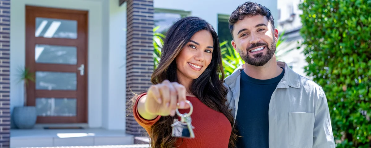 Un couple de clients satisfaits achetant un bien immobilier, un prêt hypothécaire et un concept de relocalisation. Le bâtiment est visible à l'arrière-plan.