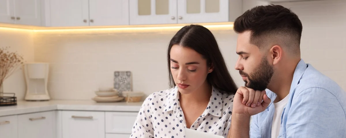 Jeune couple discutant du budget familial dans la cuisine.