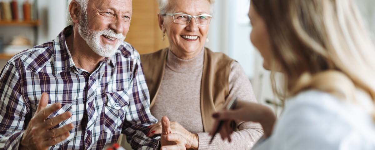 Couple de seniors heureux discutant avec leur agent d’assurance à domicile.