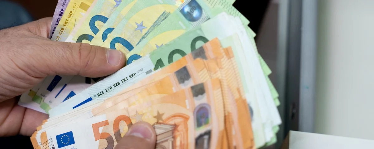 Gros plan sur les mains d'un homme manipulant une grande quantité de billets d'euros