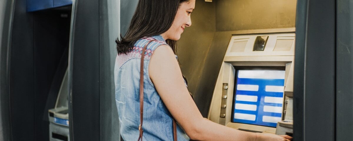 Femme utilisant un distributeur d'argent à la banque