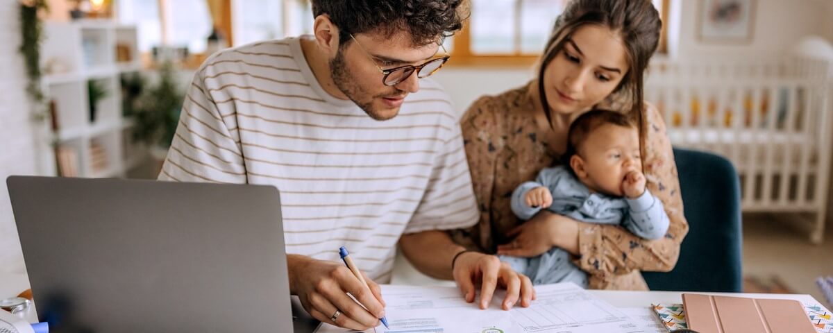 Jeune famille avec un mignon petit garçon en train d'examiner les finances à la maison.